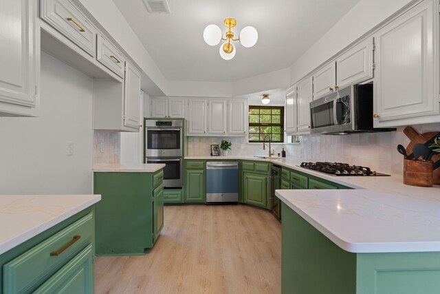 kitchen with light wood finished floors, stainless steel appliances, visible vents, white cabinetry, and green cabinetry