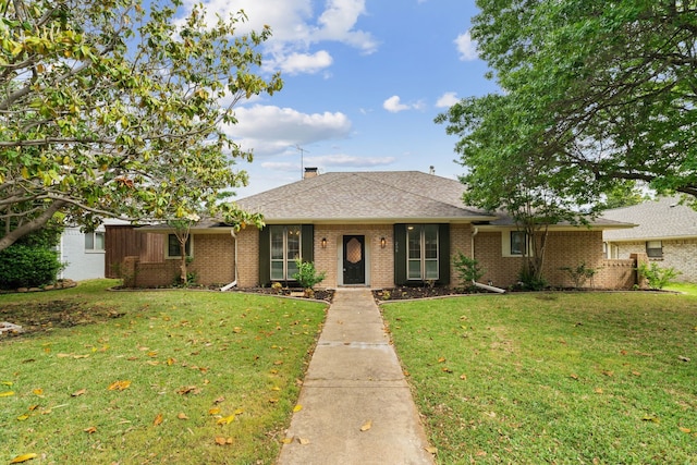 single story home with roof with shingles, a front lawn, a chimney, and brick siding