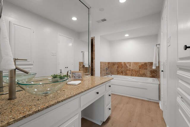 full bath featuring visible vents, recessed lighting, a bath, wood finished floors, and vanity