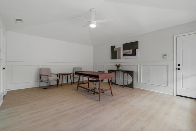 dining space with lofted ceiling, a decorative wall, visible vents, wood finished floors, and a ceiling fan