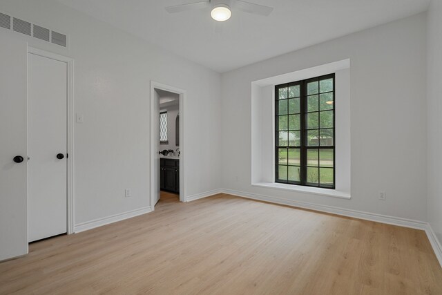 unfurnished bedroom featuring connected bathroom, ceiling fan, visible vents, light wood-style flooring, and baseboards