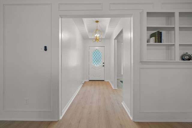 entryway featuring baseboards, light wood-type flooring, and a notable chandelier