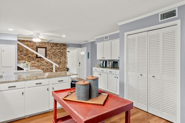 kitchen with a ceiling fan, crown molding, light wood finished floors, and visible vents