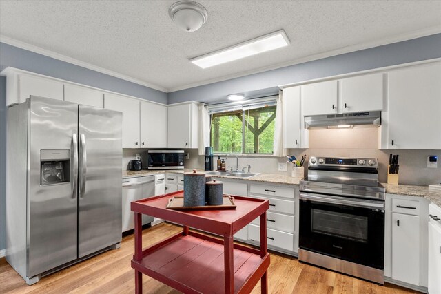 kitchen featuring under cabinet range hood, stainless steel appliances, ornamental molding, a sink, and a textured ceiling