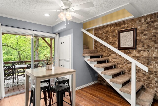 dining space featuring hardwood / wood-style floors, a textured ceiling, and brick wall