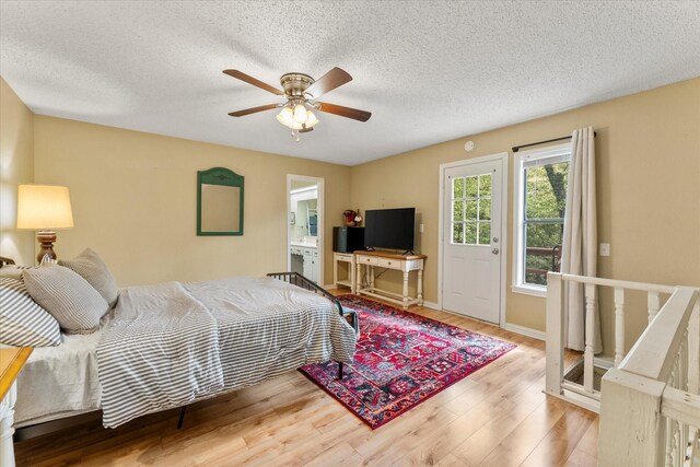 bedroom featuring a textured ceiling, ensuite bathroom, baseboards, a ceiling fan, and wood finished floors