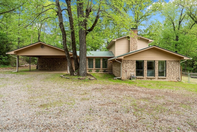 view of front of house featuring a chimney, brick siding, and a carport