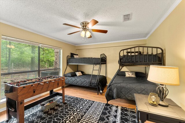 bedroom featuring a textured ceiling, wood finished floors, visible vents, and crown molding