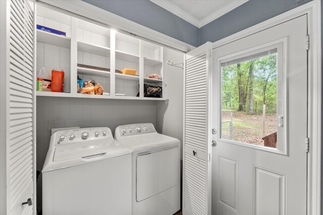 clothes washing area featuring washer and dryer, ornamental molding, laundry area, and a healthy amount of sunlight