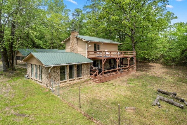 back of property with brick siding, a lawn, a chimney, and a deck