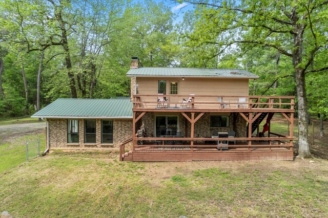 rear view of house with a lawn, a chimney, metal roof, and a deck