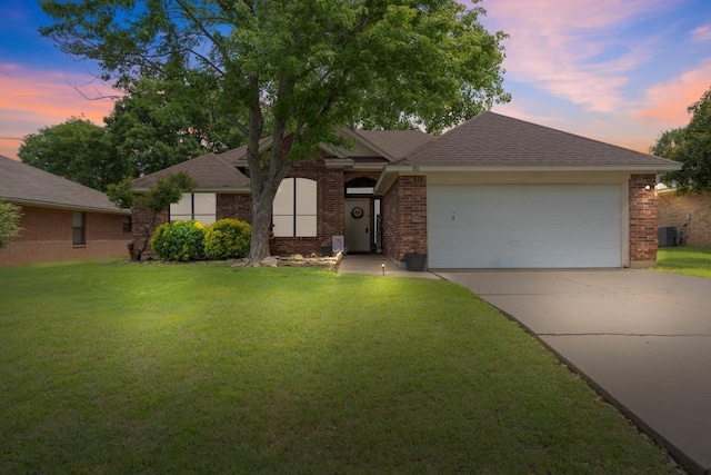 view of front of property with brick siding, driveway, a lawn, and a garage
