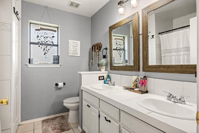bathroom with visible vents, a sink, double vanity, and toilet