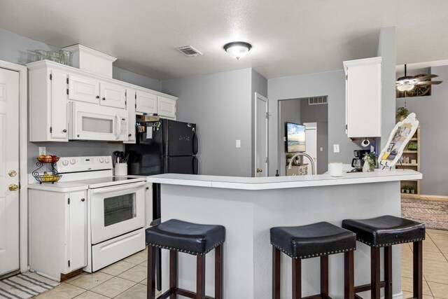 kitchen featuring white cabinets, a breakfast bar, white appliances, and light tile patterned floors