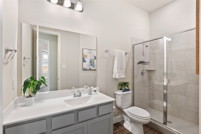 full bathroom with toilet, vanity, and a stall shower