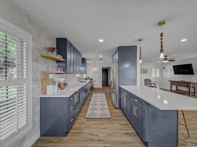 kitchen with open shelves, a breakfast bar, light countertops, blue cabinetry, and a peninsula