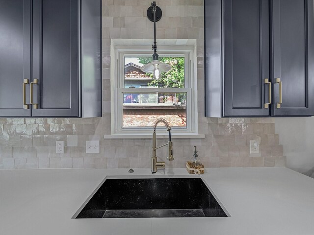 kitchen with light countertops, backsplash, pendant lighting, and a sink