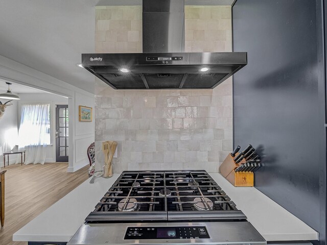 kitchen featuring wall chimney exhaust hood, decorative backsplash, and wood finished floors