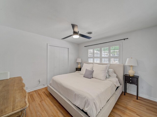 bedroom featuring a ceiling fan, a closet, light wood-style flooring, baseboards, and visible vents