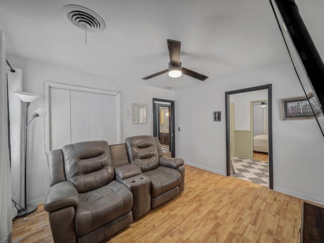 living room with baseboards, a ceiling fan, light wood-style floors, and visible vents