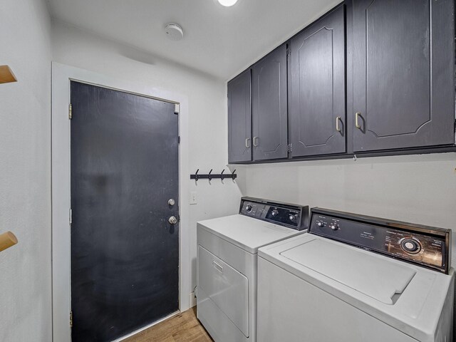 laundry room featuring separate washer and dryer, cabinet space, and light wood-style flooring