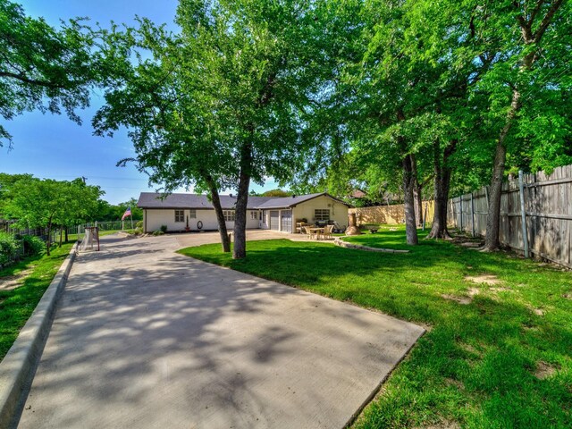 view of front of house featuring a front lawn, driveway, and fence