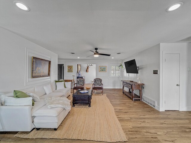 living room with a ceiling fan, visible vents, light wood finished floors, and recessed lighting