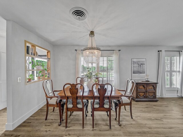 dining space with baseboards, light wood-style flooring, visible vents, and a chandelier