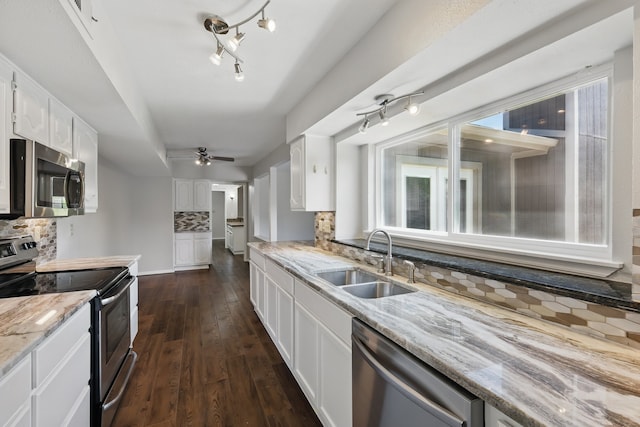 kitchen with light stone countertops, tasteful backsplash, a sink, dark wood finished floors, and stainless steel appliances