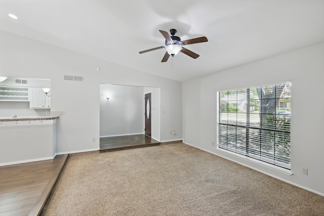 unfurnished living room featuring ceiling fan, visible vents, baseboards, and lofted ceiling