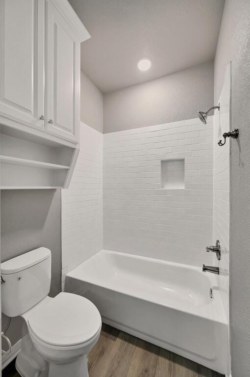 full bath featuring wood finished floors, washtub / shower combination, and toilet