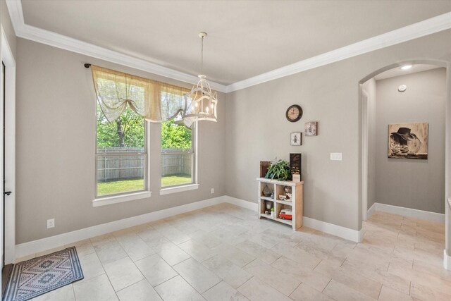 unfurnished dining area with arched walkways, crown molding, baseboards, and an inviting chandelier