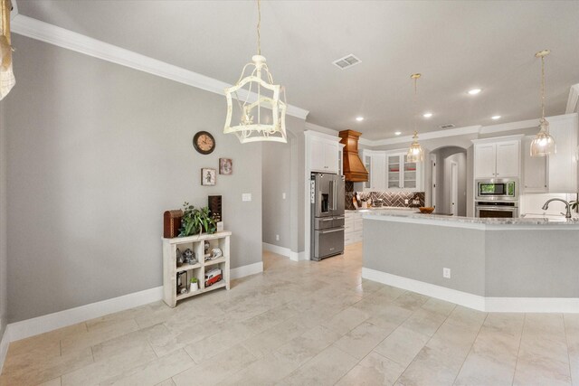 kitchen with light countertops, ornamental molding, arched walkways, decorative backsplash, and appliances with stainless steel finishes