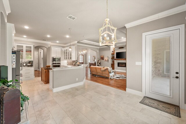 kitchen featuring stainless steel appliances, visible vents, arched walkways, and ornamental molding