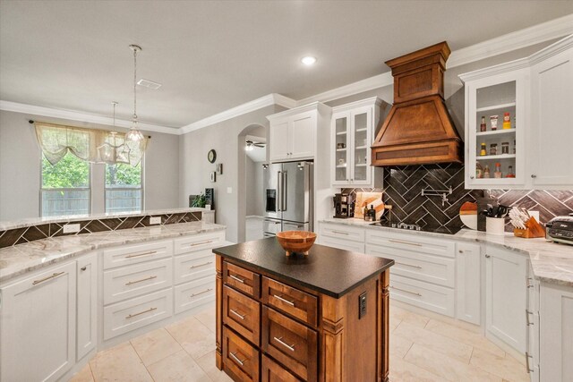 kitchen featuring arched walkways, high end refrigerator, white cabinetry, backsplash, and custom range hood