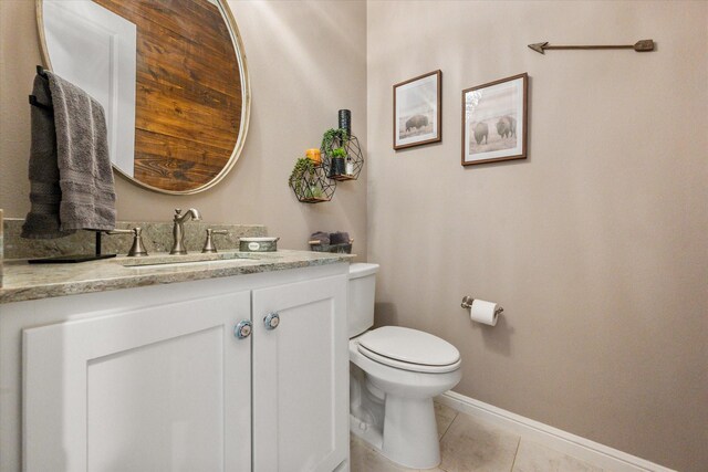 half bathroom featuring tile patterned floors, baseboards, vanity, and toilet