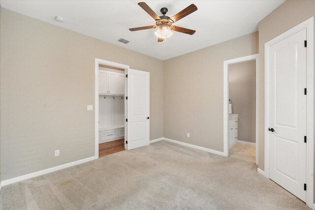 unfurnished bedroom with baseboards, visible vents, light colored carpet, and connected bathroom
