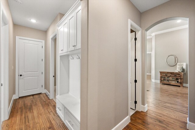 mudroom with arched walkways, wood finished floors, and baseboards