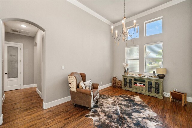 sitting room with a notable chandelier, arched walkways, crown molding, and baseboards