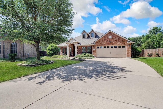 view of front of property featuring fence, concrete driveway, an attached garage, brick siding, and a front yard