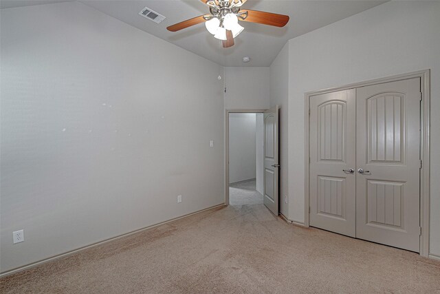 unfurnished bedroom featuring vaulted ceiling, visible vents, a ceiling fan, carpet floors, and a closet
