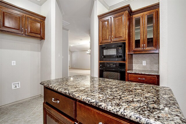 kitchen with glass insert cabinets, dark stone counters, black appliances, and tasteful backsplash