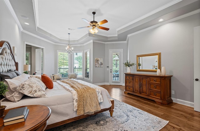 bedroom featuring a raised ceiling, wood finished floors, visible vents, baseboards, and access to outside