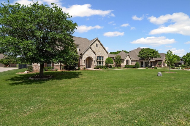 french provincial home featuring stone siding, a front lawn, and brick siding