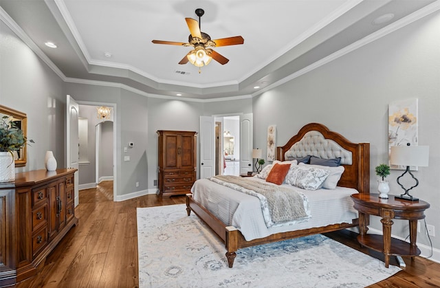 bedroom featuring a raised ceiling, baseboards, visible vents, and hardwood / wood-style flooring