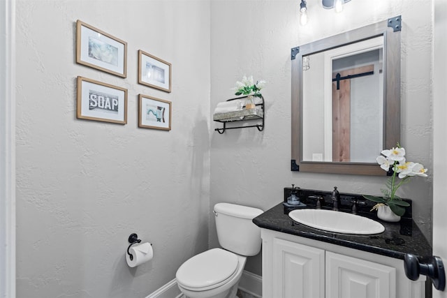 bathroom with baseboards, vanity, and toilet
