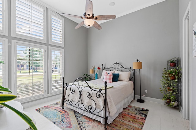bedroom featuring baseboards, ceiling fan, and multiple windows