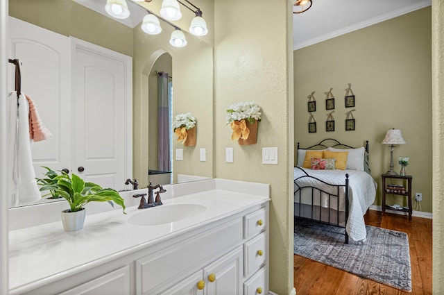 bathroom featuring baseboards, wood finished floors, vanity, and ornamental molding