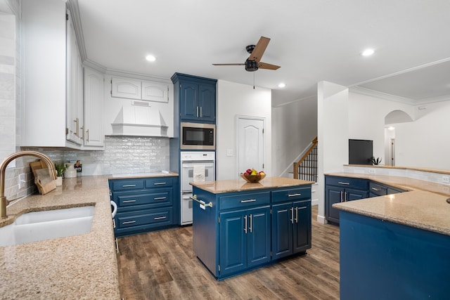 32 Royal Oaks Cir, Denton, TX 76210 - kitchen with oven, a sink, stainless steel microwave, ceiling fan, and blue cabinetry