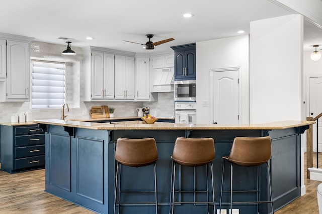 32 Royal Oaks Cir, Denton, TX 76210 - kitchen with blue cabinets, oven, a kitchen breakfast bar, decorative backsplash, and recessed lighting